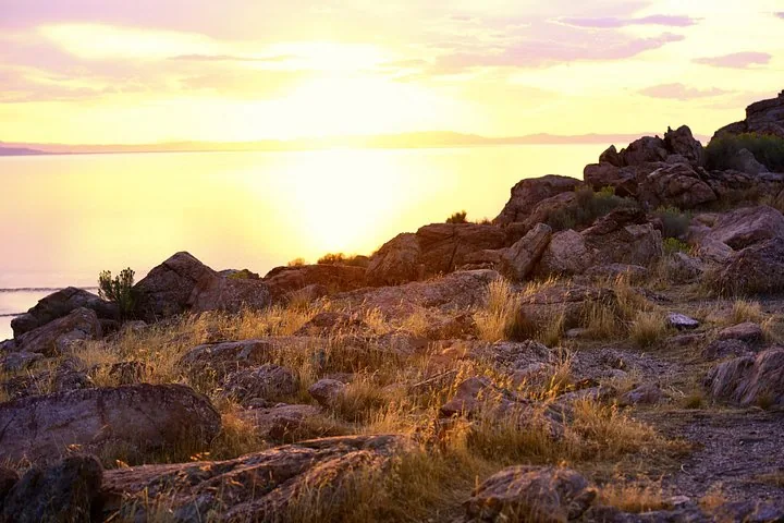 Rocky landscape near Great Salt Lake during a bright, hazy sunset.