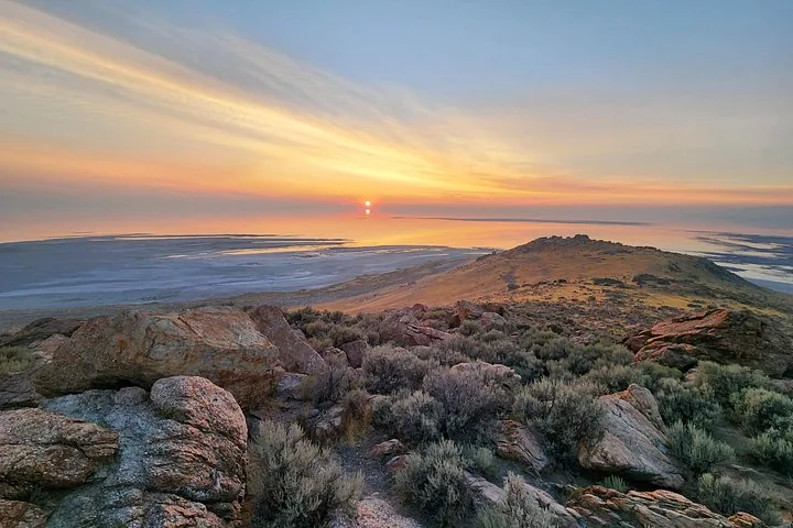 Panoramic sunset view over Great Salt Lake from a rocky vantage point.