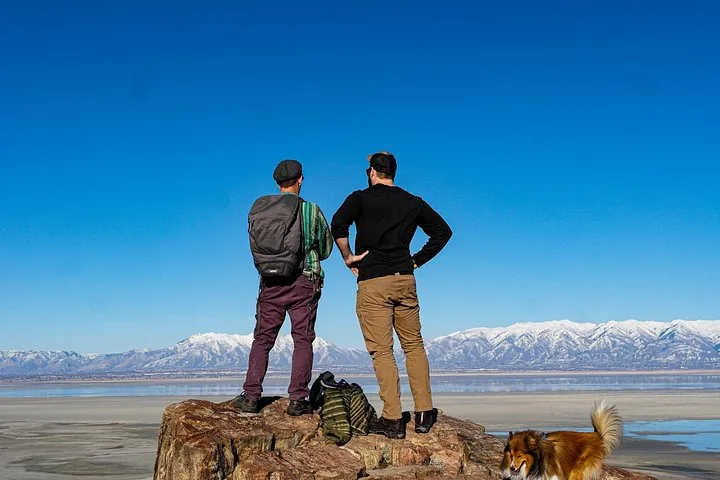 Two men standing on a rock looking at Great Salt Lake and mountains.